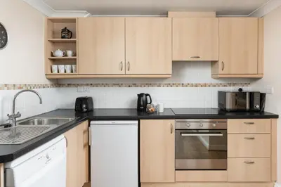 a kitchen with wooden cabinets and a sink at 7 Lower Talland Apartments in St Ives