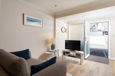 a living room with a couch and a flat screen tv at 6 Lower Talland Apartments in St Ives