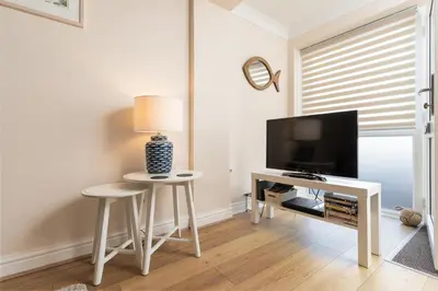 a living room with a tv and a table and stool at 6 Lower Talland Apartments in St Ives