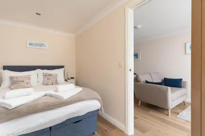 a bedroom with a bed and a chair and a mirror at 6 Lower Talland Apartments in St Ives