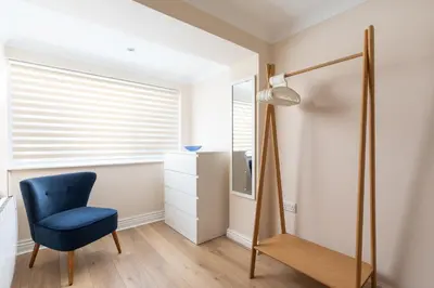 a bedroom with a blue chair and a mirror at 6 Lower Talland Apartments in St Ives