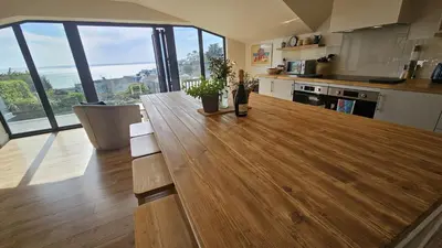 a kitchen with a wooden table in a room with windows at Chupra in Saint Mawes