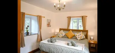 a bedroom with a large bed with two windows at Seaview Barns in Budock Water