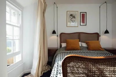 a bedroom with a bed with orange pillows and a window at Charming Cottage & Garden in Port Isaac in Port Isaac