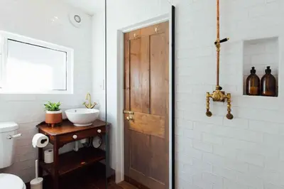 a bathroom with a wooden door and a sink at Charming Cottage & Garden in Port Isaac in Port Isaac