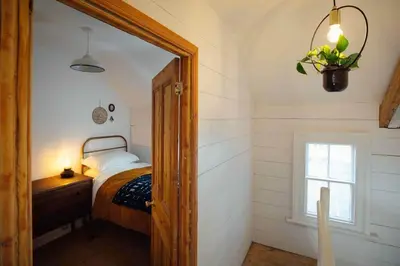 a bedroom with a bed and a window and a mirror at Charming Cottage & Garden in Port Isaac in Port Isaac