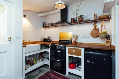 a small kitchen with a black stove and a sink at Charming Cottage & Garden in Port Isaac in Port Isaac