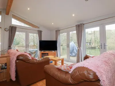 a living room with a leather couch and a television at 1 Miller's Island in Looe