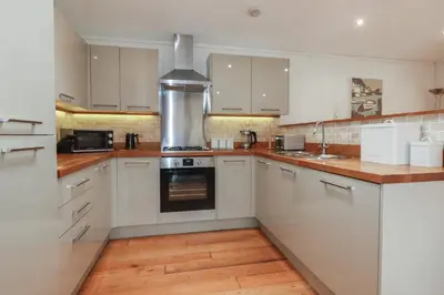 a kitchen with white cabinets and a stove top oven at 1 Miller's Island in Looe