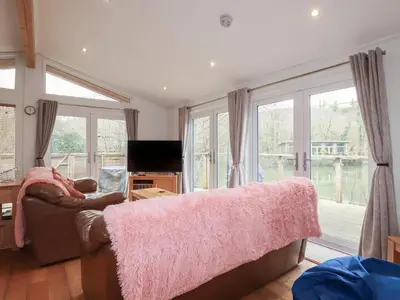 a living room with a couch and large windows at 1 Miller's Island in Looe