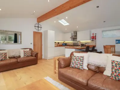 a living room with two brown couches and a kitchen at 2 Miller's Island in Looe