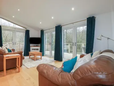 a living room with a leather couch and windows at 2 Miller's Island in Looe