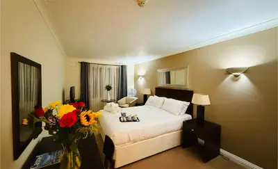 a hotel room with a bed and flowers on a table at Hustyns Hotel in Wadebridge