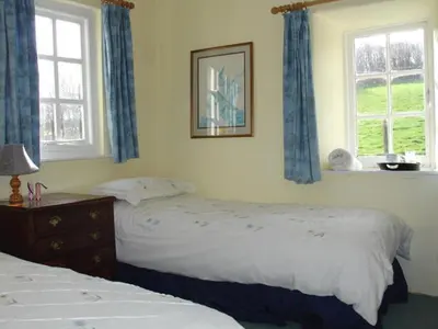 two beds in a bedroom with two windows at Roskear Farm in Wadebridge
