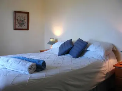 a large white bed with blue pillows on it at Roskear Farm in Wadebridge