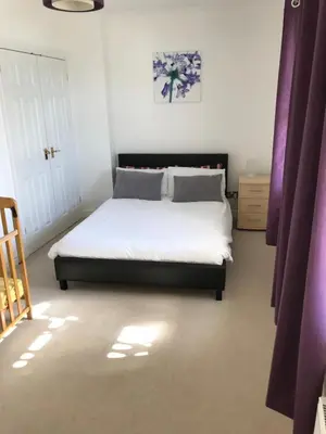 a bedroom with a bed with white sheets and purple curtains at 5 Hatfield Cresent in Newquay