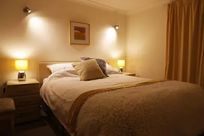a bedroom with a large bed with two lamps at Manor Lodge in Newquay