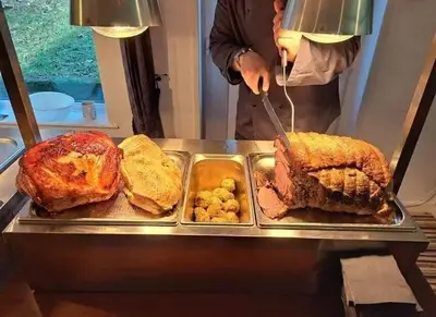 a person cutting a sandwich on a tray with food at Manor Lodge in Newquay