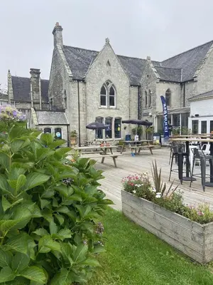 a courtyard with picnic tables and umbrellas in front of a building at Manor Lodge in Newquay