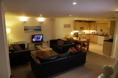 a living room with two couches and a kitchen at Manor Lodge in Newquay
