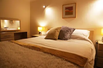 a bedroom with a bed with two lamps and a mirror at Manor Lodge in Newquay