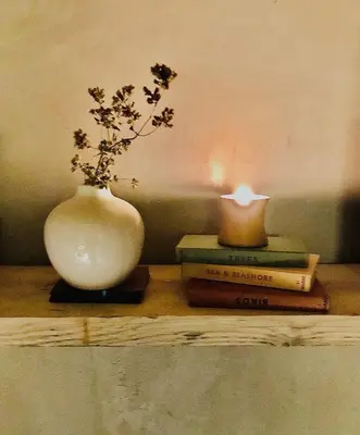 a vase sitting on a table with books and a candle at Studio Portland in Falmouth
