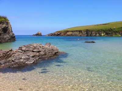 a beach with some rocks in the water at Rock Cottage in St. Issey
