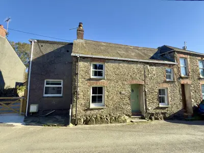 an old stone house with a green door at Rock Cottage in St. Issey