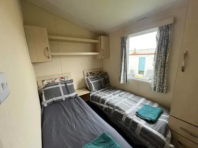 two beds in a small room with a window at Sea Shanty in Newquay