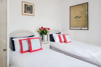 two beds with red and white pillows and a vase of flowers at Beautiful family house with amazing sea views in Padstow