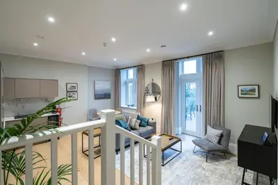 a living room with a staircase and a couch at Treloyhan Manor St Ives in St Ives
