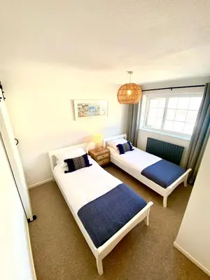 a bedroom with two beds and a chandelier at Mermaid Cove in Portreath
