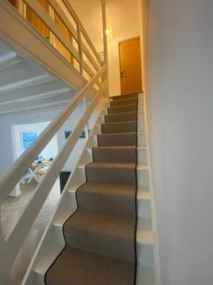 a staircase in a house with white stairs and a wooden door at Mermaid Cove in Portreath