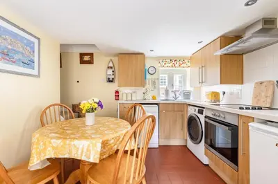 a kitchen with a table and a table and chairs at Blaise Cottage Cornwall in St Austell