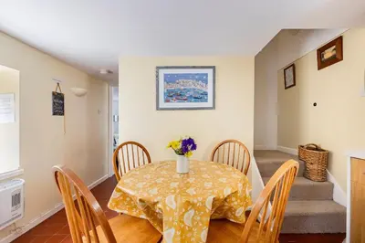 a dining room table with a vase of flowers on it at Blaise Cottage Cornwall in St Austell