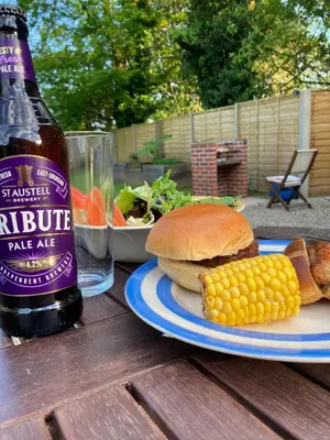 a bottle of beer and a sandwich and corn on a table at Blaise Cottage Cornwall in St Austell