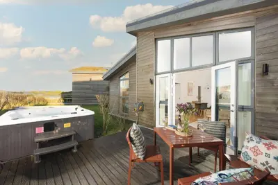 a deck with a hot tub and a table at 71 Una, Carbis Bay in Carbis Bay