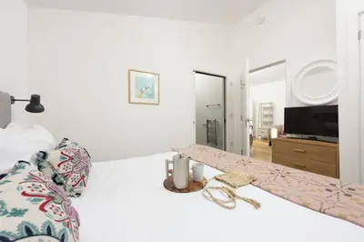 a bedroom with a white bed with a tv on it at 71 Una, Carbis Bay in Carbis Bay