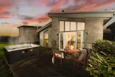 a deck with a hot tub and a table and chairs at 71 Una, Carbis Bay in Carbis Bay