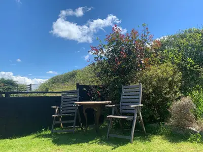 two chairs and a table in front of a bush at Field View in Liskeard