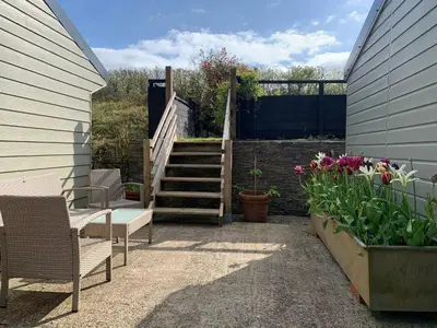a patio with two chairs and a staircase with flowers at Field View in Liskeard