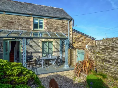 a brick cottage with a patio with a table and chairs at Skiber An Hyli in Mawgan Porth