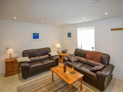 a living room with two leather couches and a coffee table at Skiber An Hyli in Mawgan Porth
