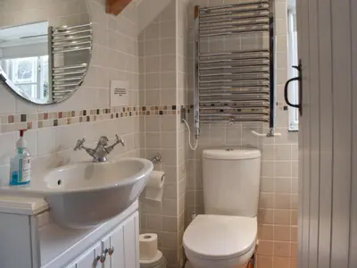 a bathroom with a sink and a toilet and a mirror at Skiber An Hyli in Mawgan Porth