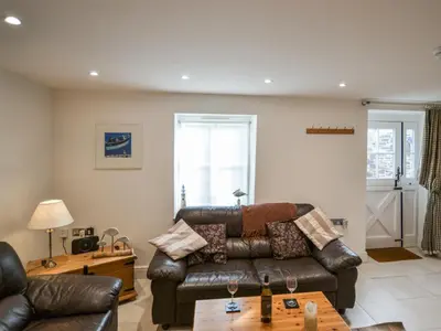 a living room with a leather couch and a table at Skiber An Hyli in Mawgan Porth
