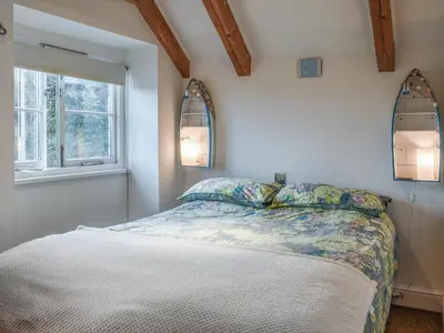 a bedroom with a bed and two windows at Skiber An Hyli in Mawgan Porth