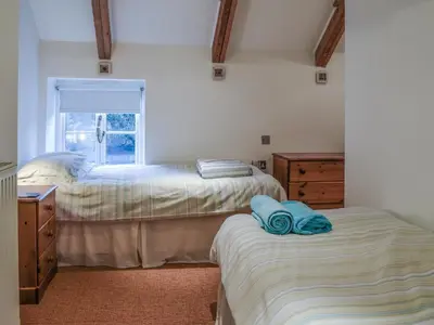 a bedroom with two beds and a window at Skiber An Hyli in Mawgan Porth