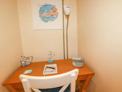 a wooden table with a white chair and a lamp at Driftwood in Newquay