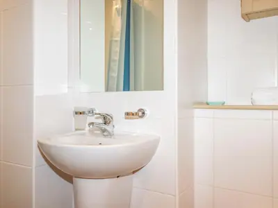 a white bathroom with a sink and a mirror at Driftwood in Newquay