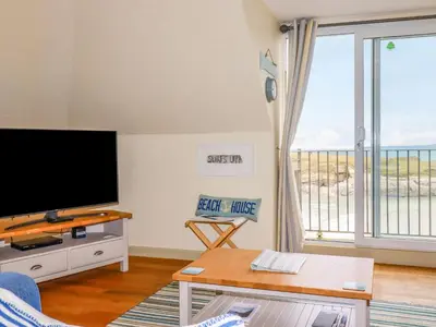 a living room with a flat screen tv and a large window at Driftwood in Newquay